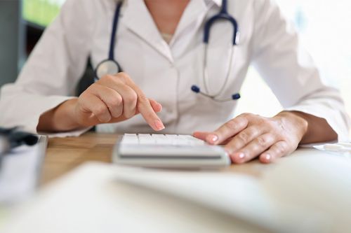 Ärztin arbeitet auf Taschenrechner im Büro